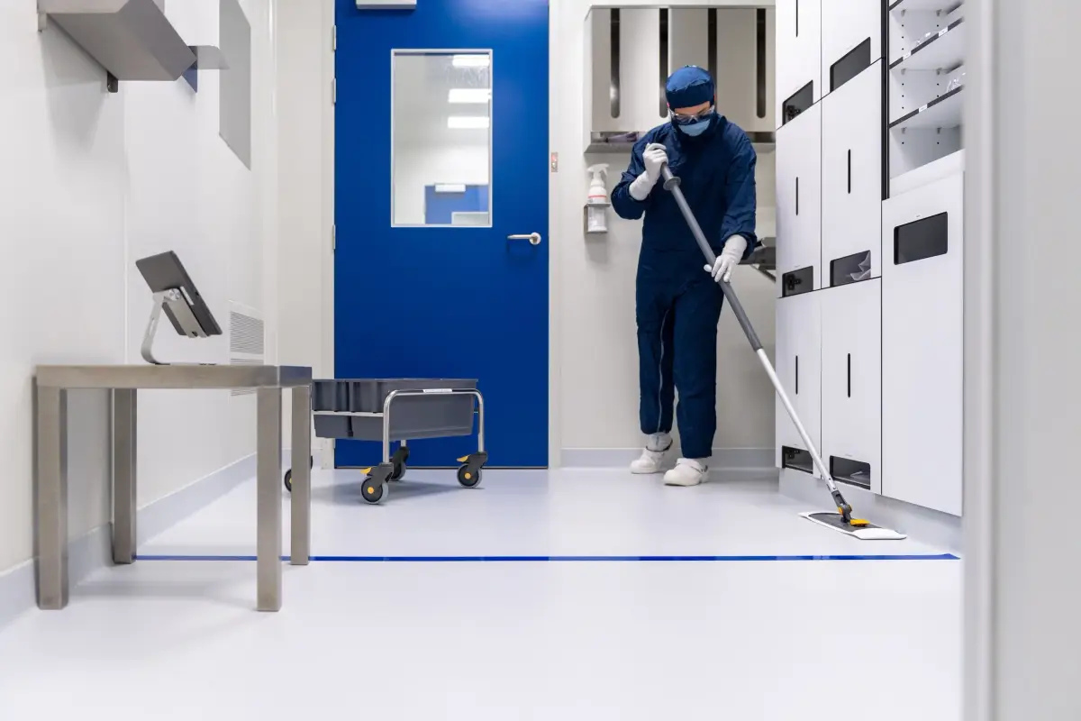 Gowned cleanroom professional mopping the floor of a controlled environment