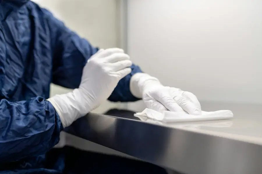 Gloved cleanroom professional carefully wiping a controlled surface